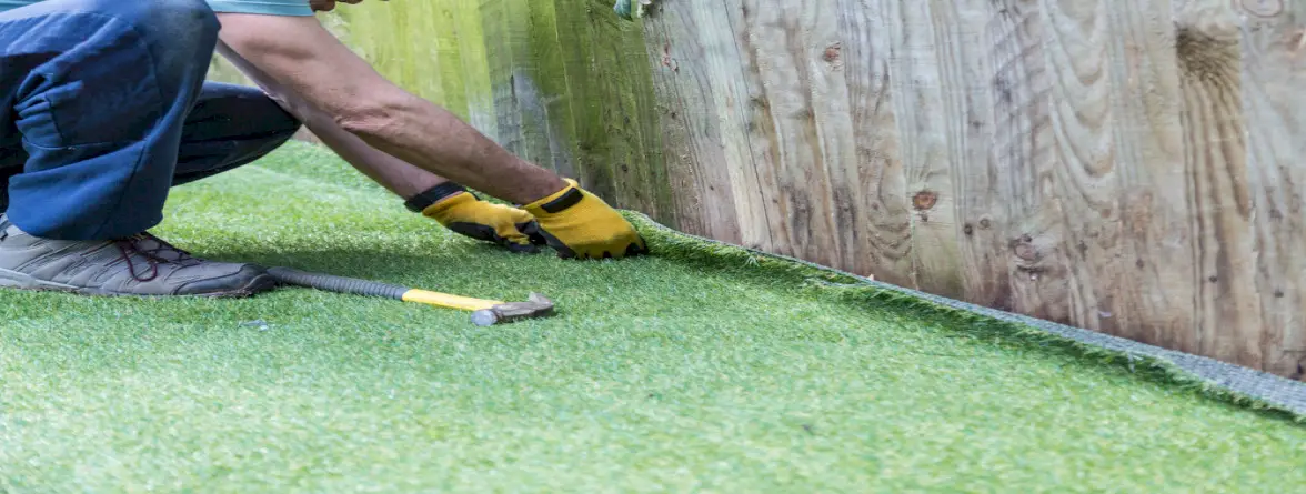 A man installing artificial grass over pavers.